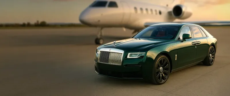 Green Rolls-Royce sedan parked in front of a private jet on a runway.